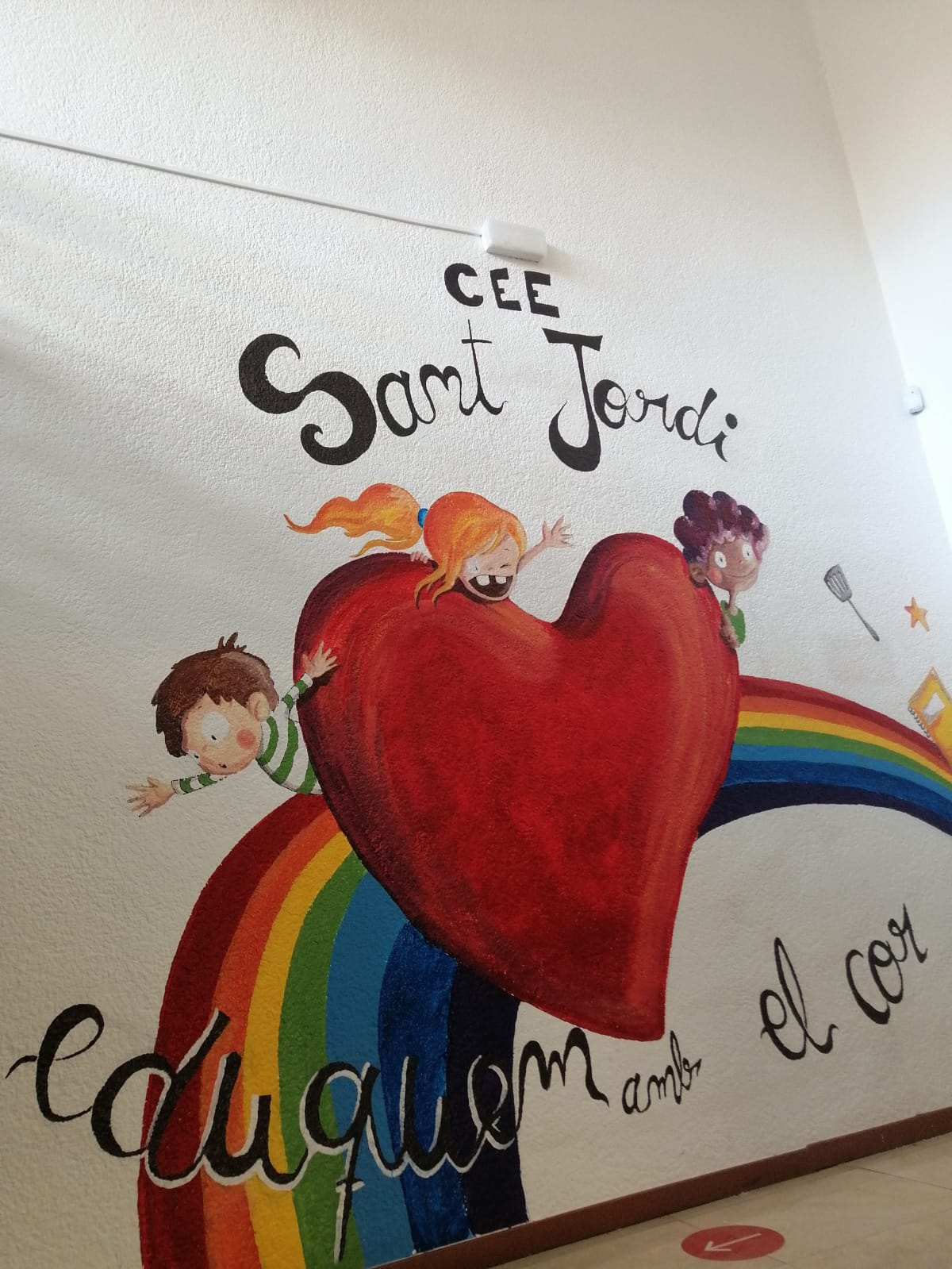 El mural recull el lema 'eduquem amb el cor'